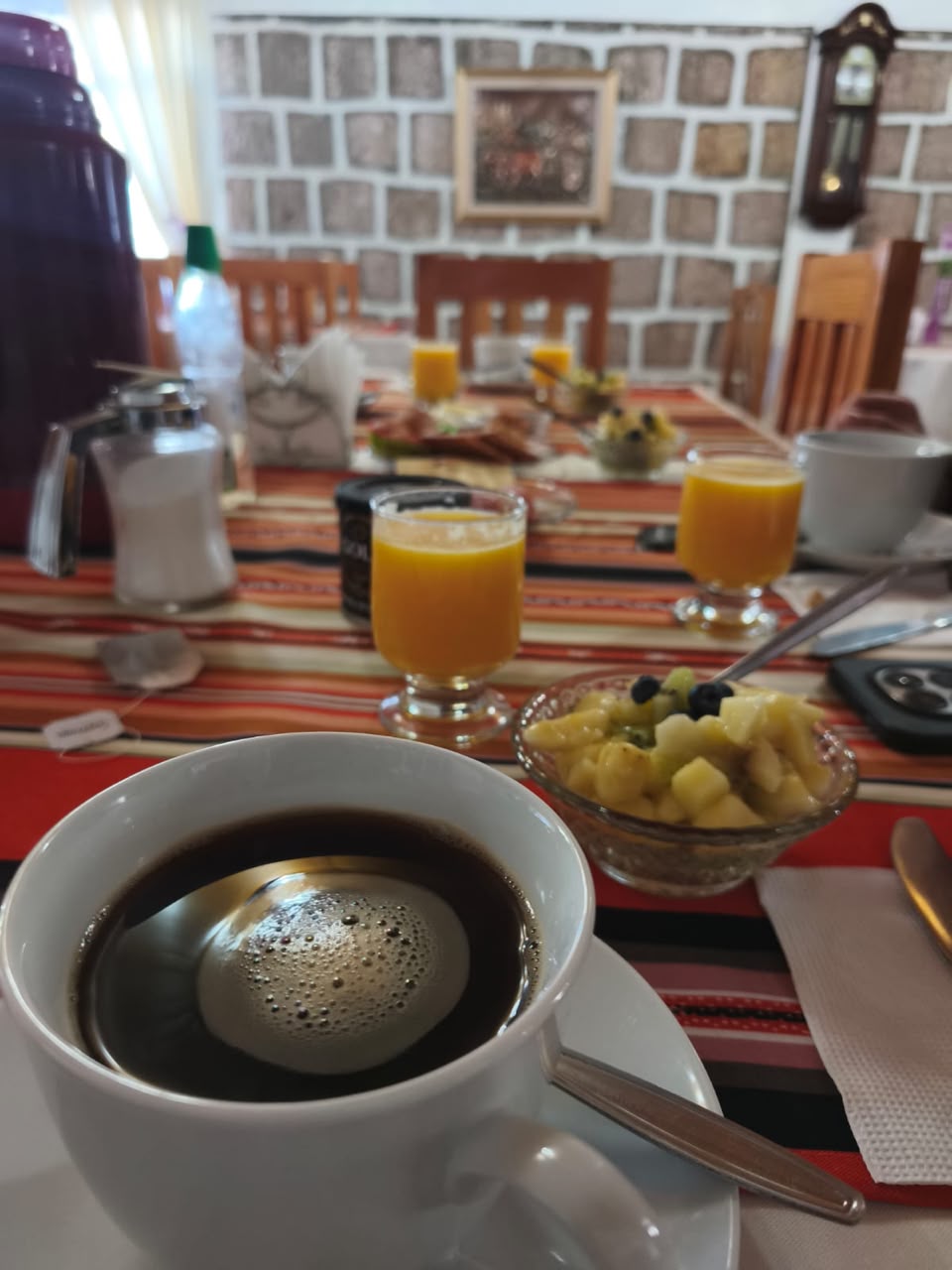 Mesa de desayuno del hotel con café, jugo y fruta