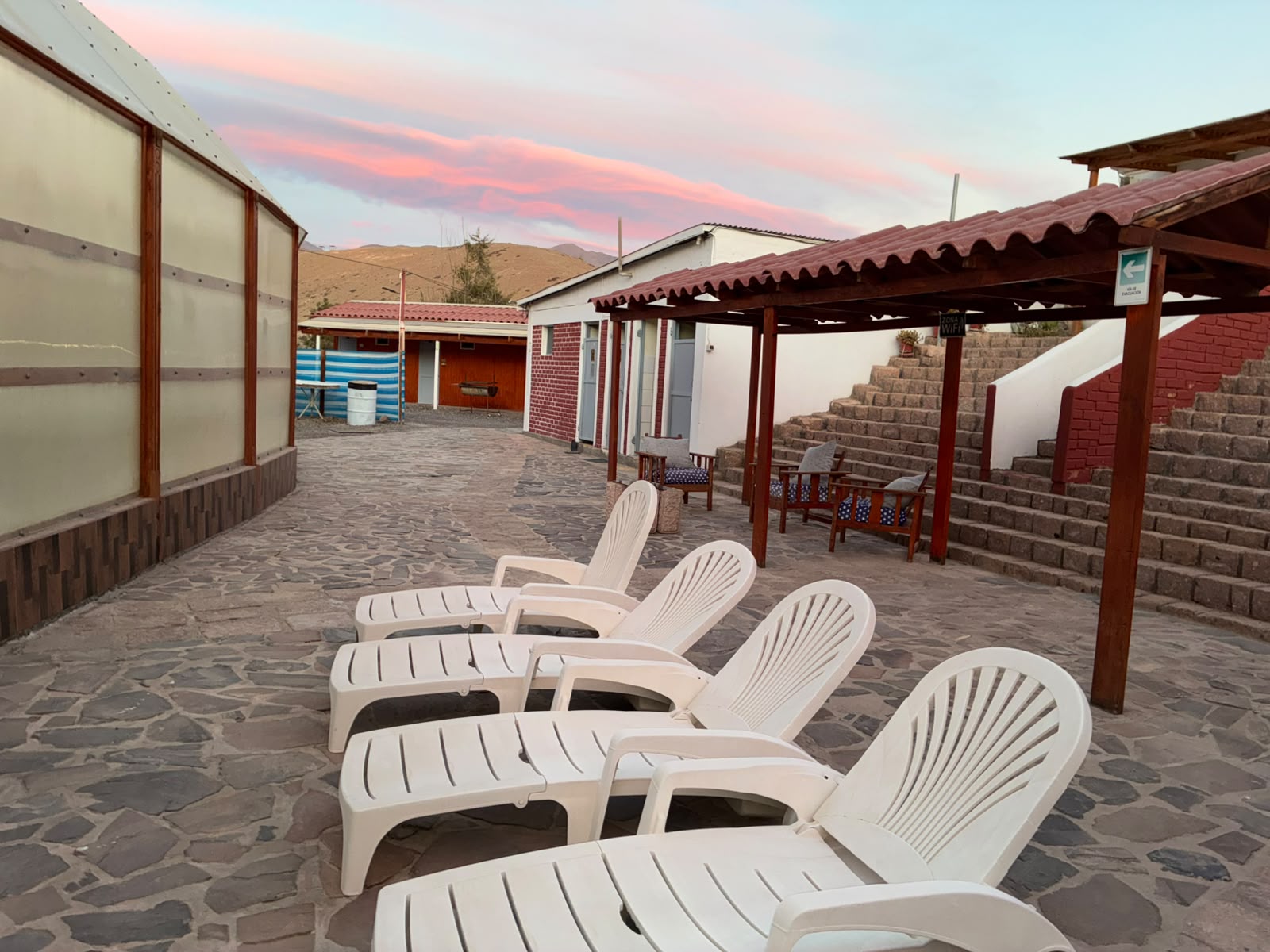 Sillas de descanso en el patio de piedra bajo el cielo rosado del atardecer