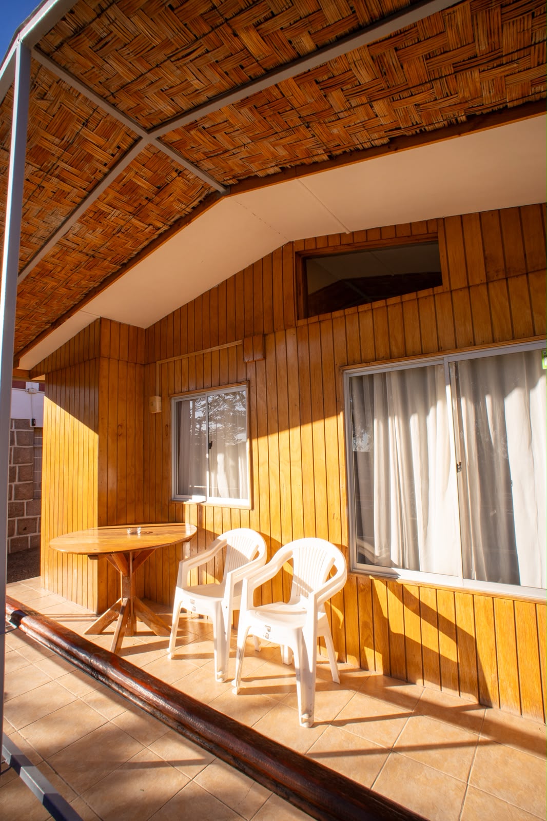 Terraza de madera con mesa y sillas iluminadas por el sol