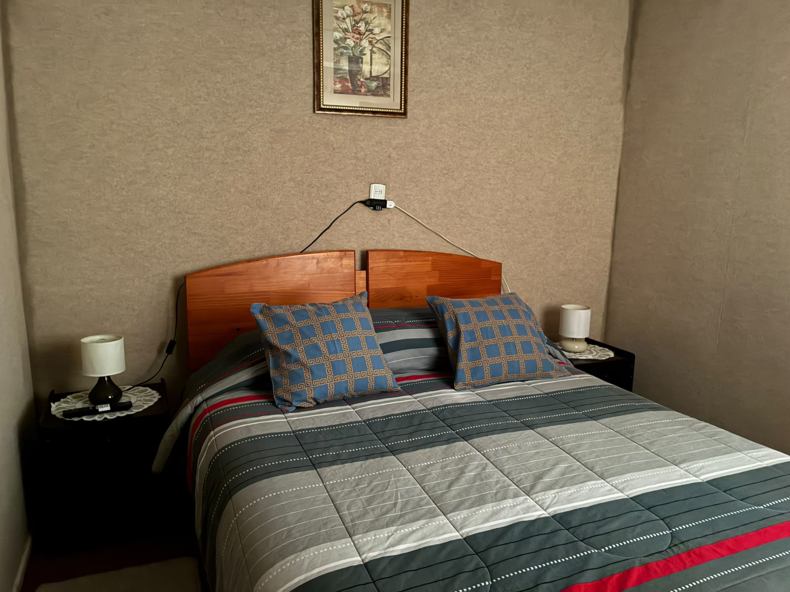 Habitación matrimonial con cubrecama gris y cojines azules
