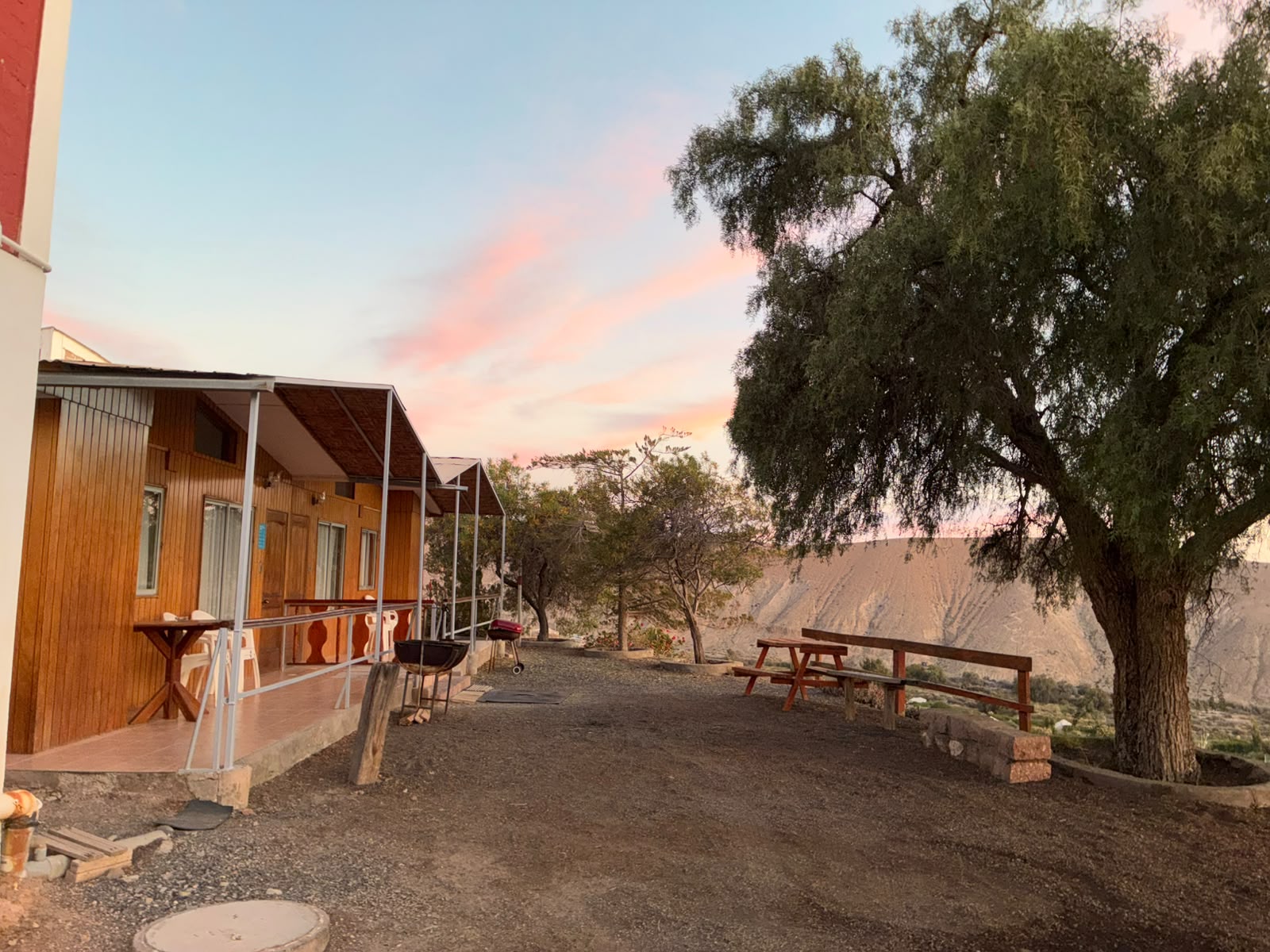 Cabañas de madera con mesas exteriores y vista a los cerros al atardecer